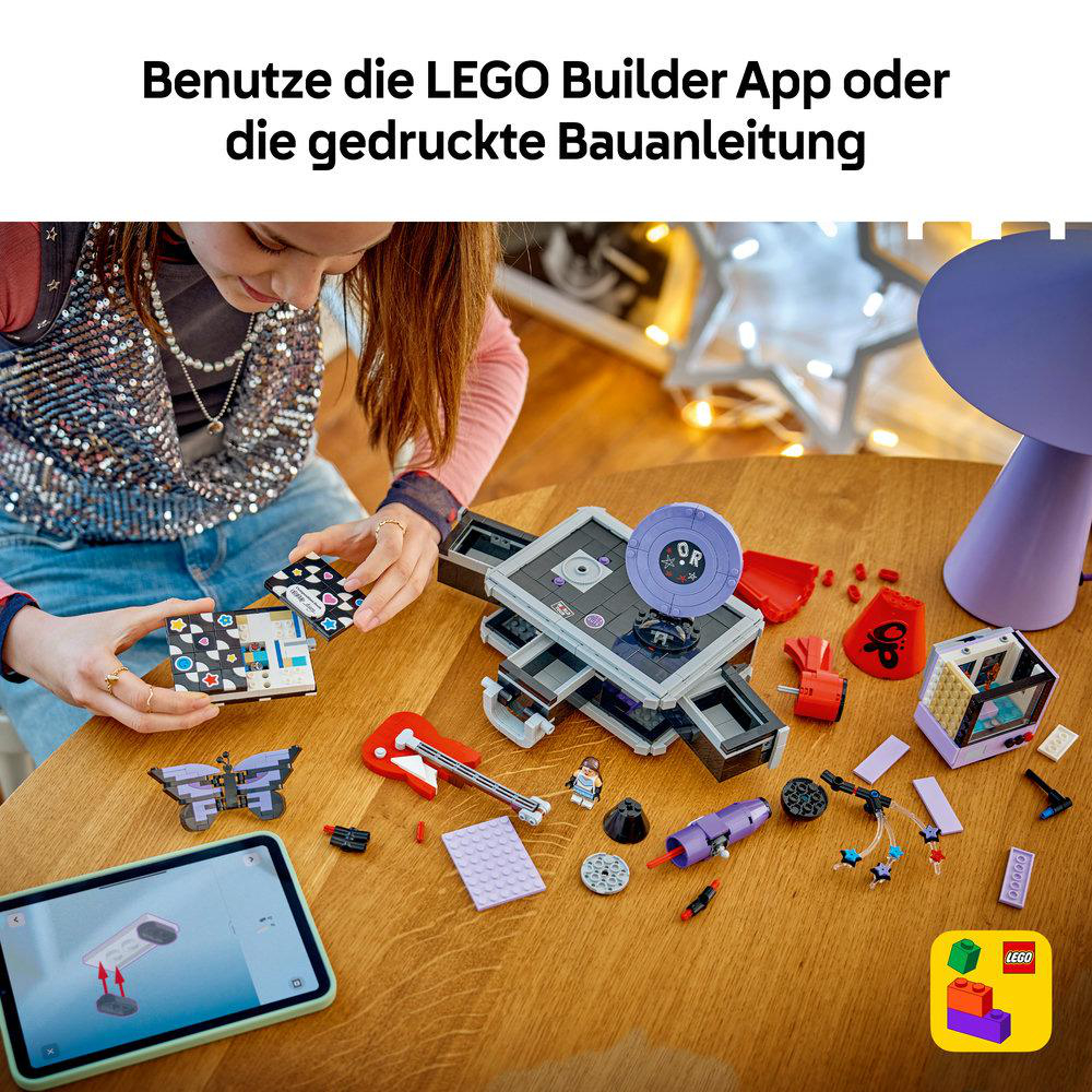 Ein Mädchen baut ein Lego-Set an einem Holztisch mit einer Bauanleitung auf einem Tablet.