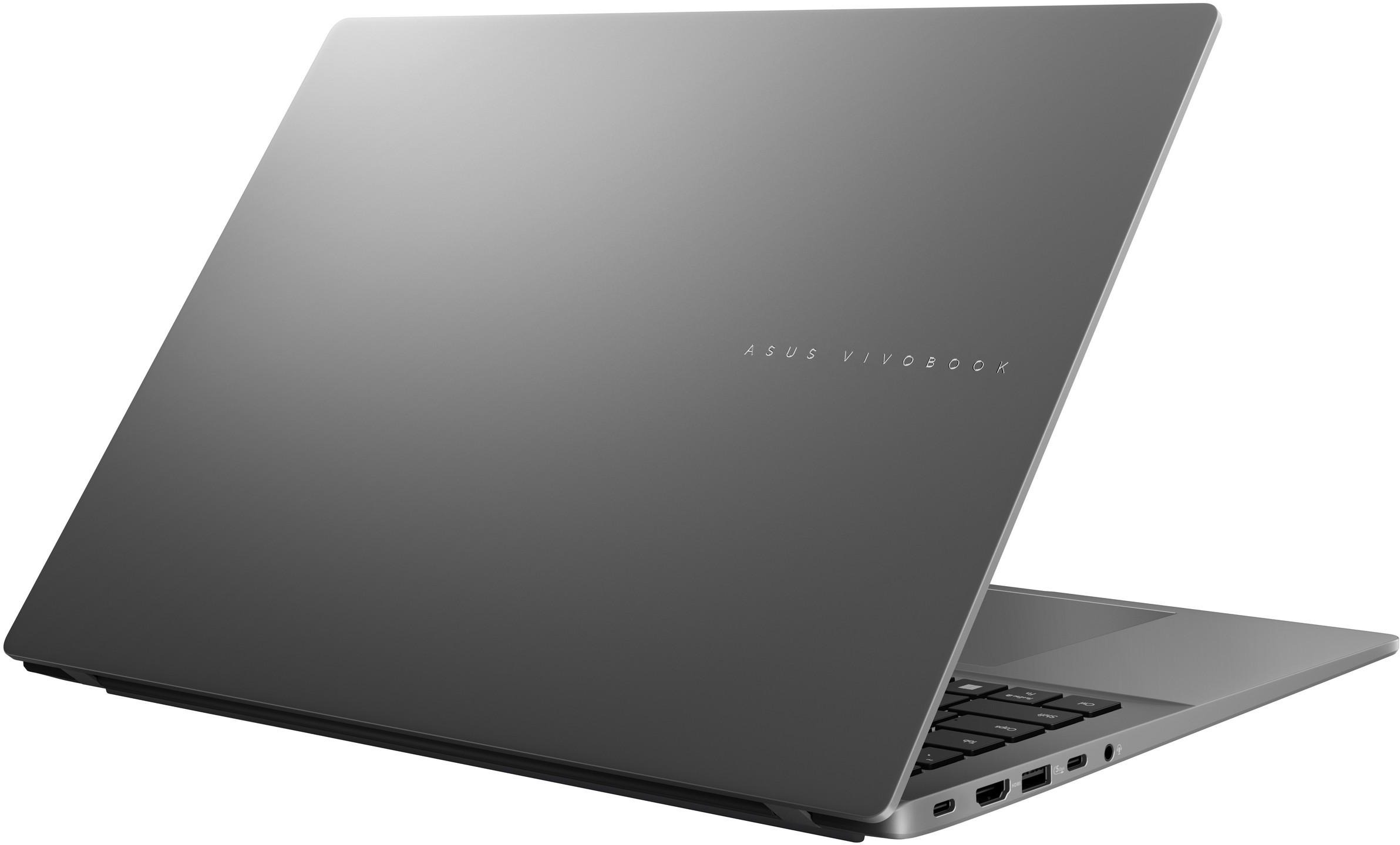 Egy szürke Asus Vivobook laptop nyitva áll egy fehér felületen, látható portokkal.