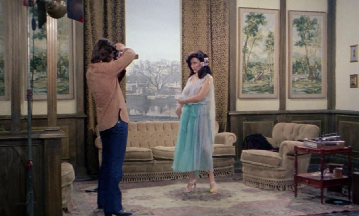 Ein Fotograf macht Aufnahmen von einer Frau in einem hellen Kleid in einem klassischen Zimmer.