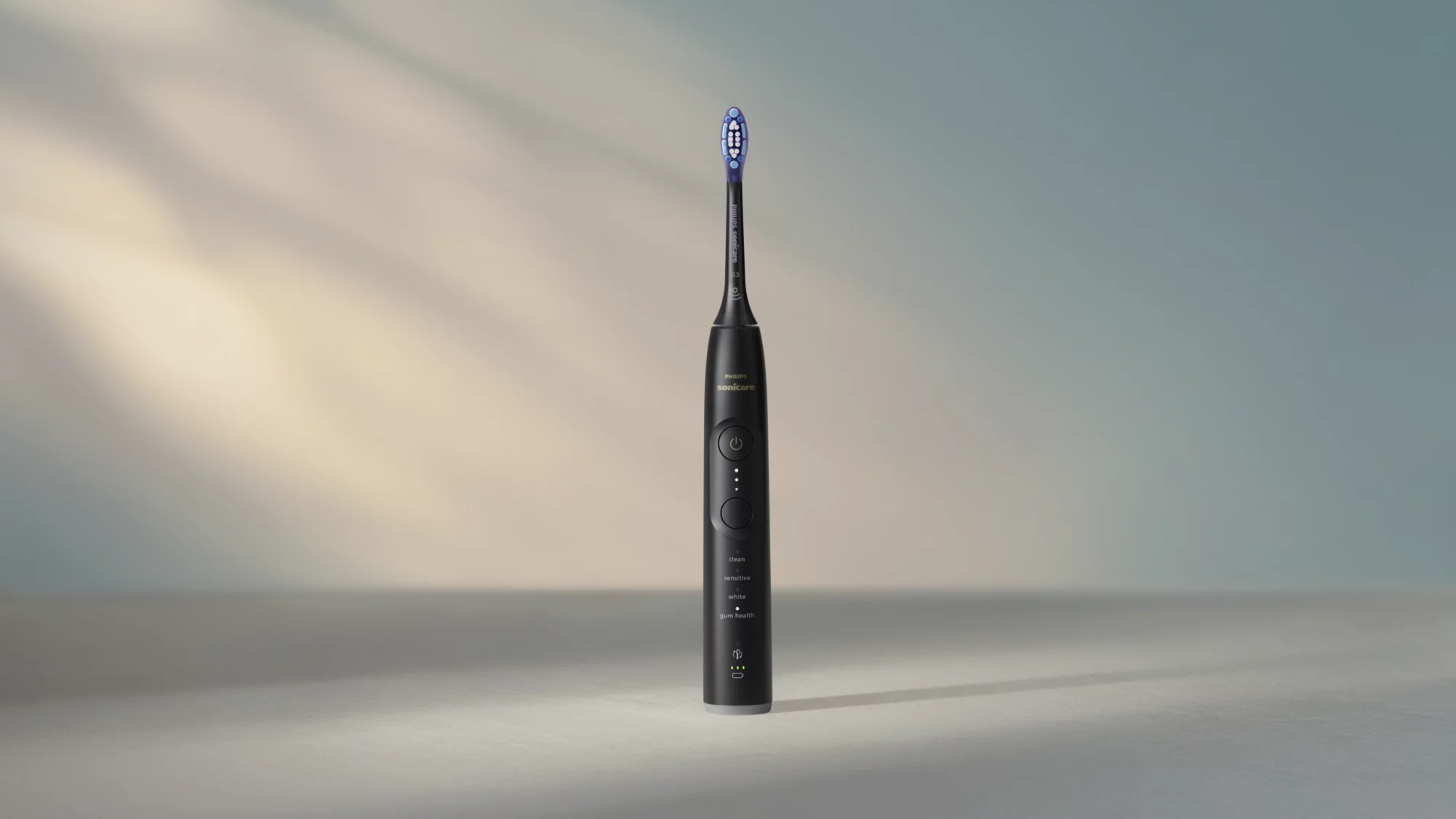 Eine schwarze Philips Sonicare elektrische Zahnbürste steht aufrecht auf einer flachen Oberfläche vor einem weichen Hintergrund.