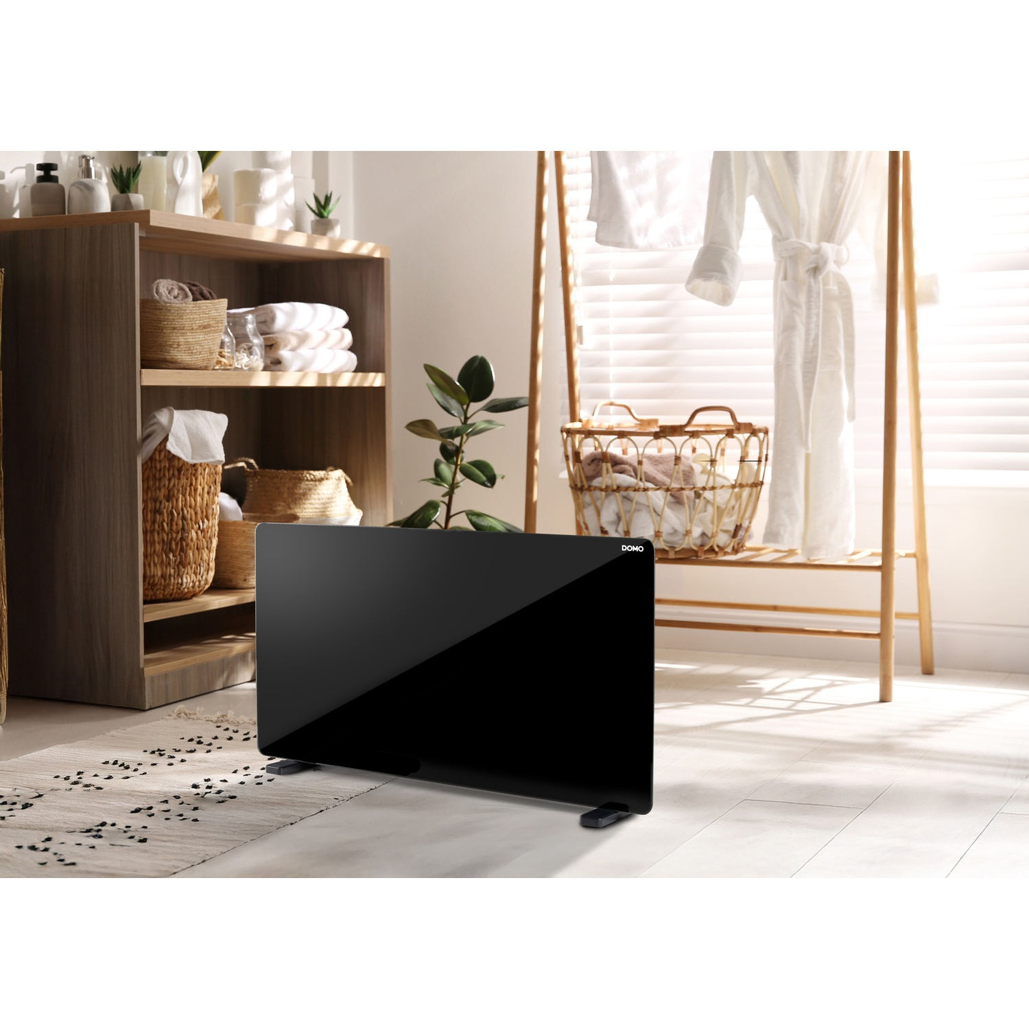 A black space heater stands on the floor in a bright bathroom with wooden shelves and bathrobes.