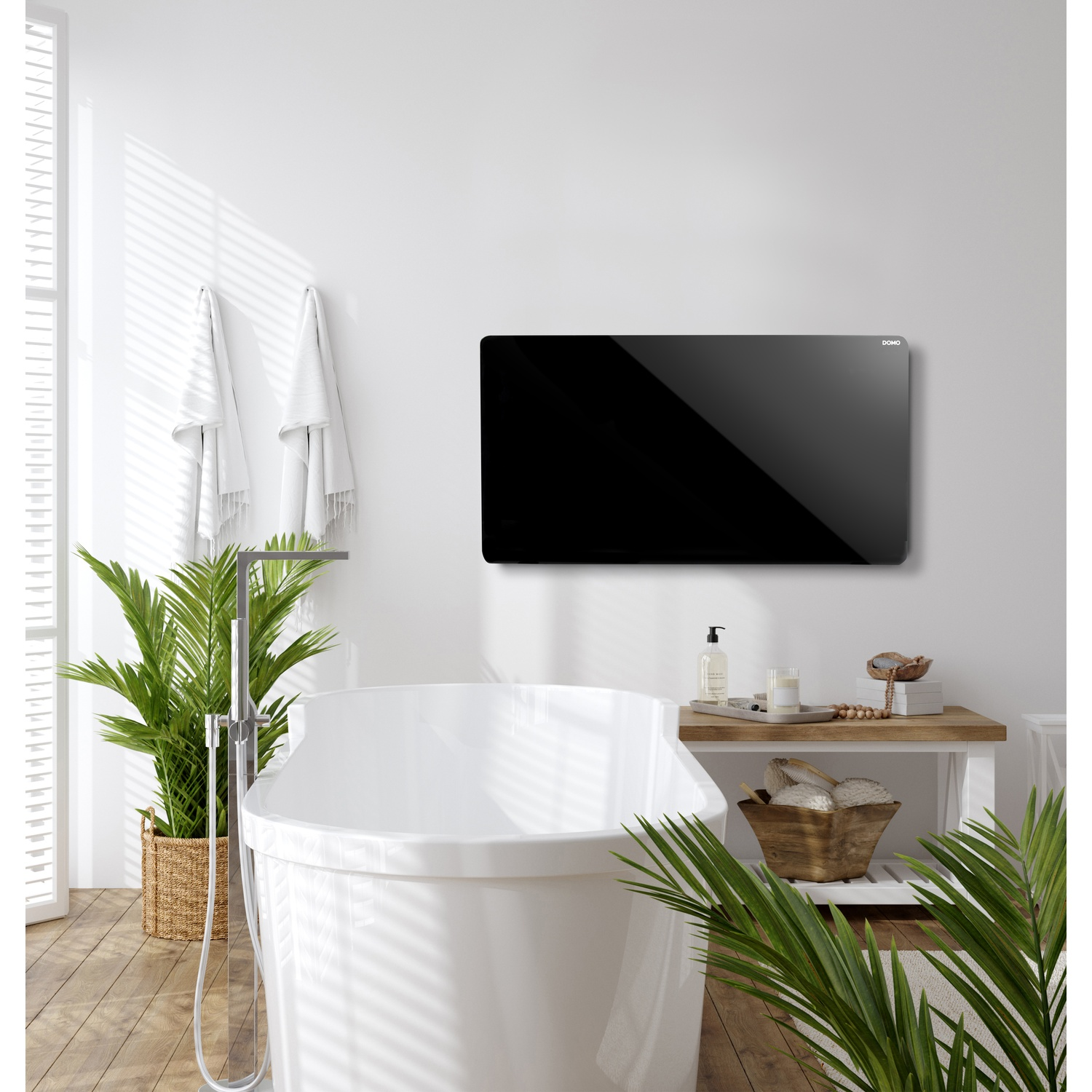 A white bathroom with a freestanding tub, plants, hanging towels, and a wall-mounted black panel.