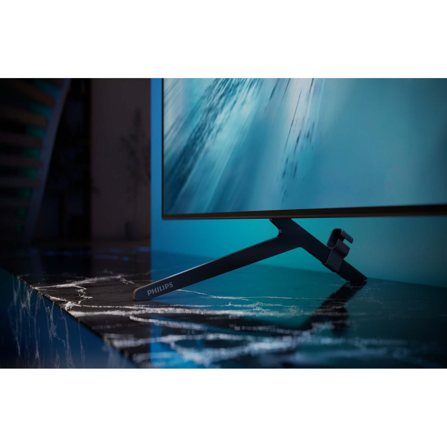 A Philips television on a dark marble table against a blue background.
