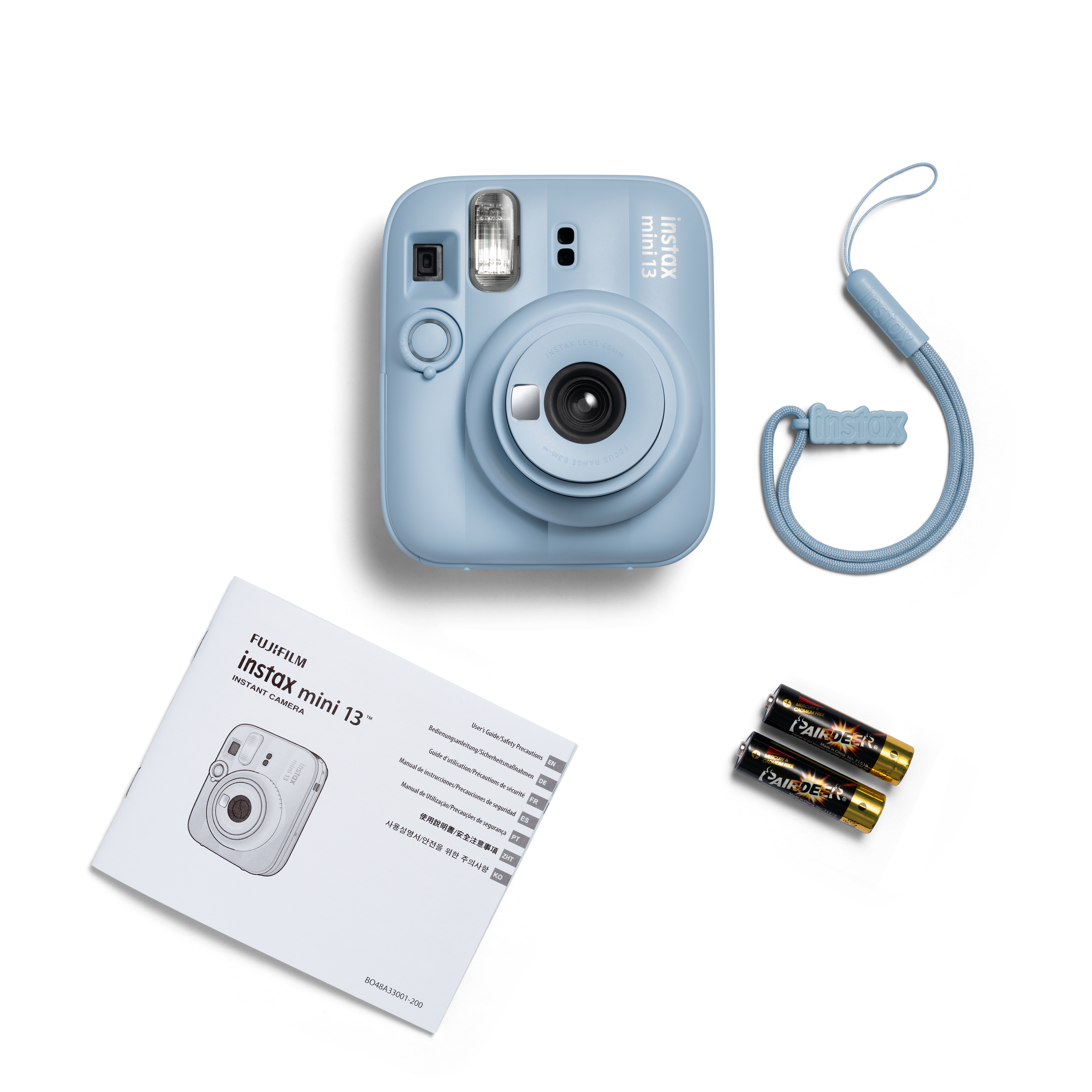 Blaue Instax Mini 13 Sofortbildkamera mit Trageband, zwei Batterien und Bedienungsanleitung auf weißem Hintergrund.