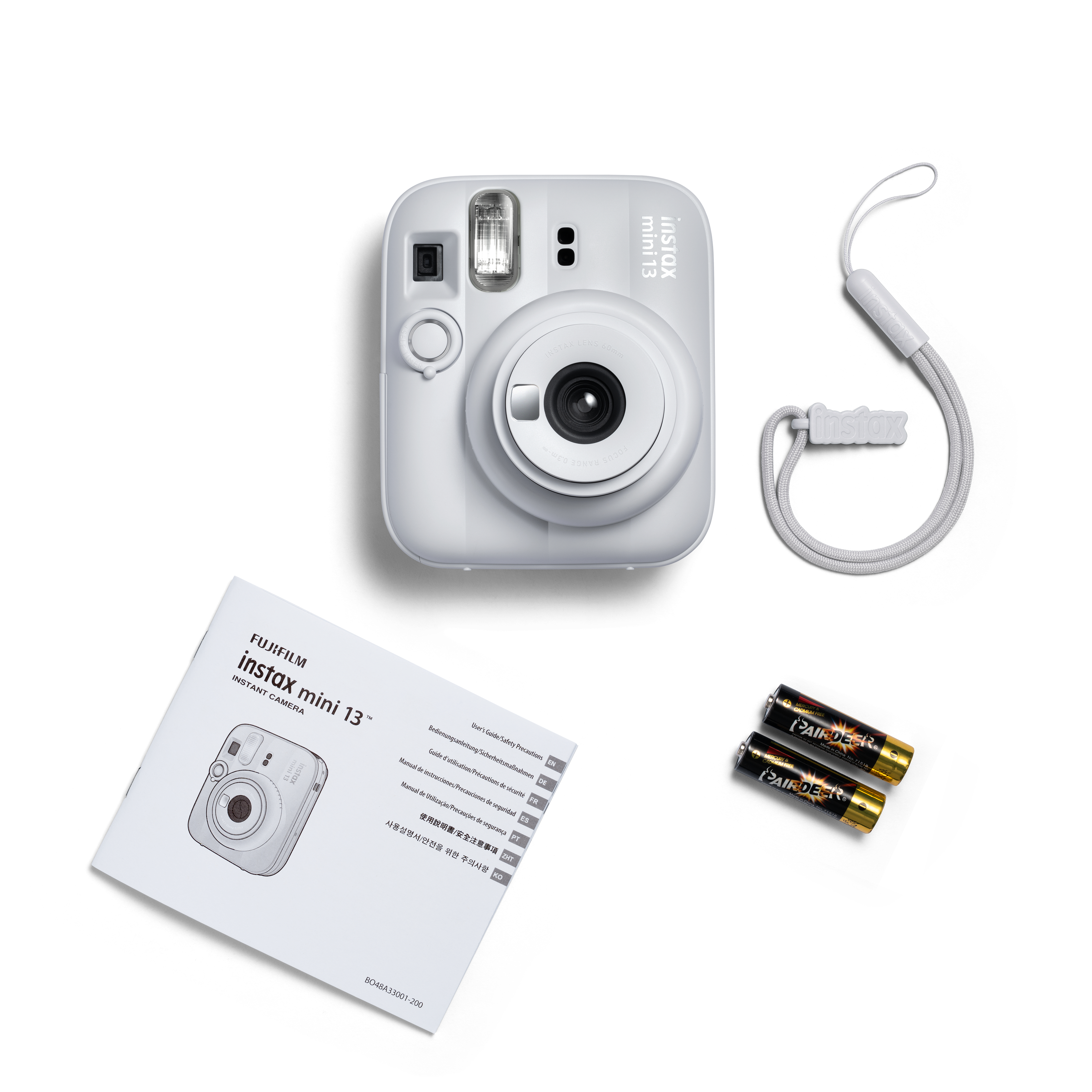 Eine weiße Instax Mini 13 Sofortbildkamera mit Bedienungsanleitung, Batterien und Handschlaufe.