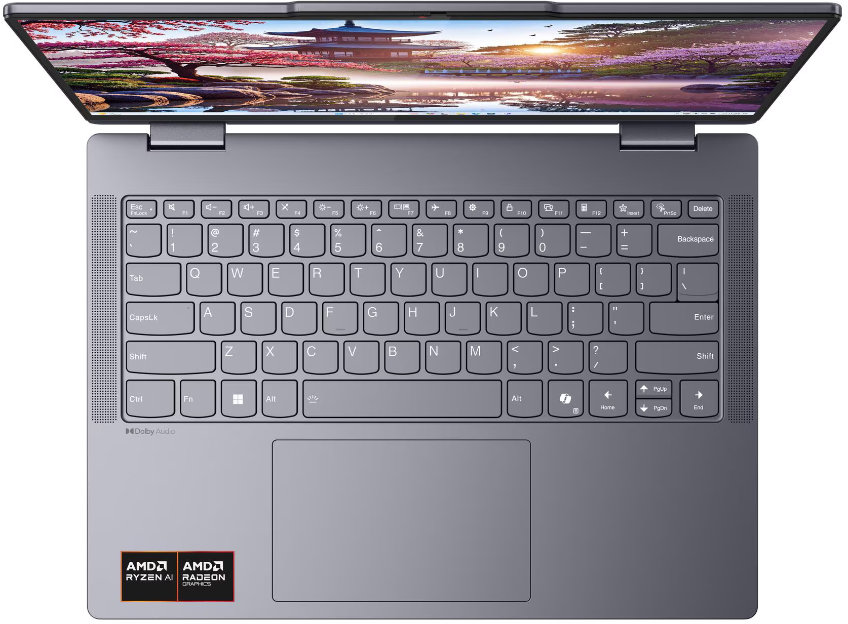 Felülnézet egy nyitott szürke laptopról, billentyűzettel, érintőpaddal és japán tájképes képernyővel.