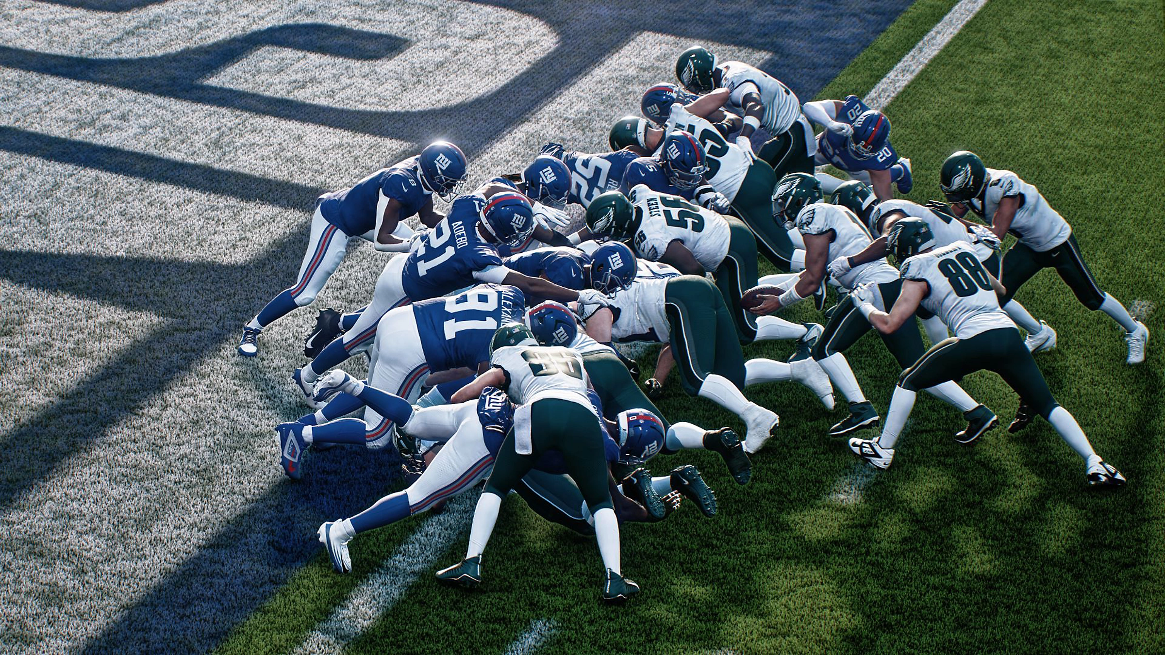 Giocatori di football americano in uniforme blu e bianca si placcano su un campo verde.