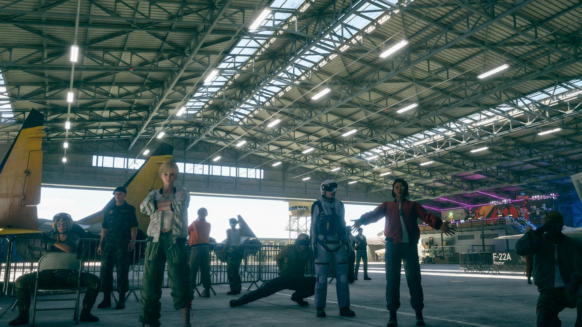 Un gruppo di persone in piedi in un grande hangar industriale con luci luminose sul soffitto.