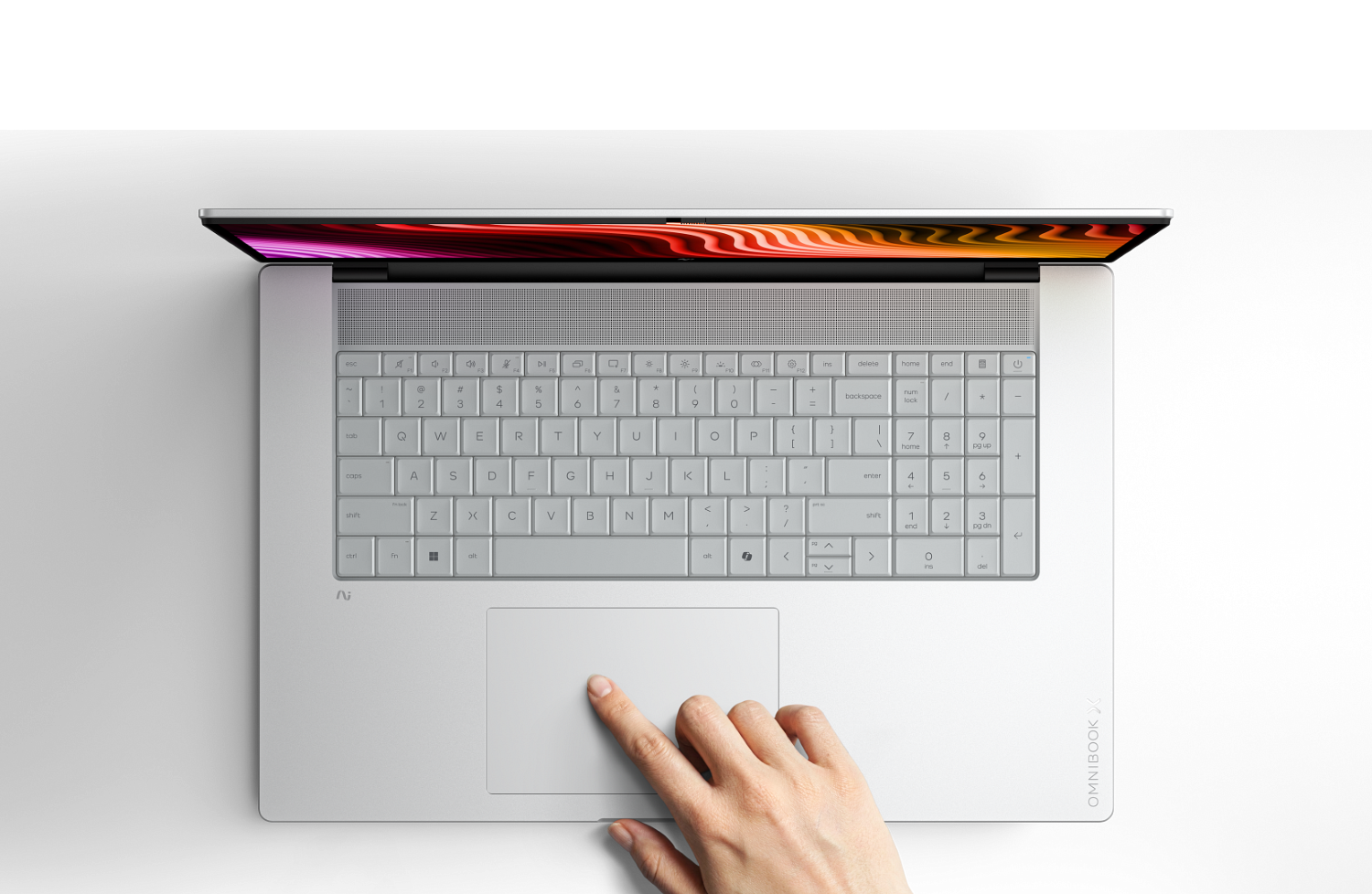 Widok z góry na srebrnego laptopa na czarnym tle, ręka dotyka panelu dotykowego.