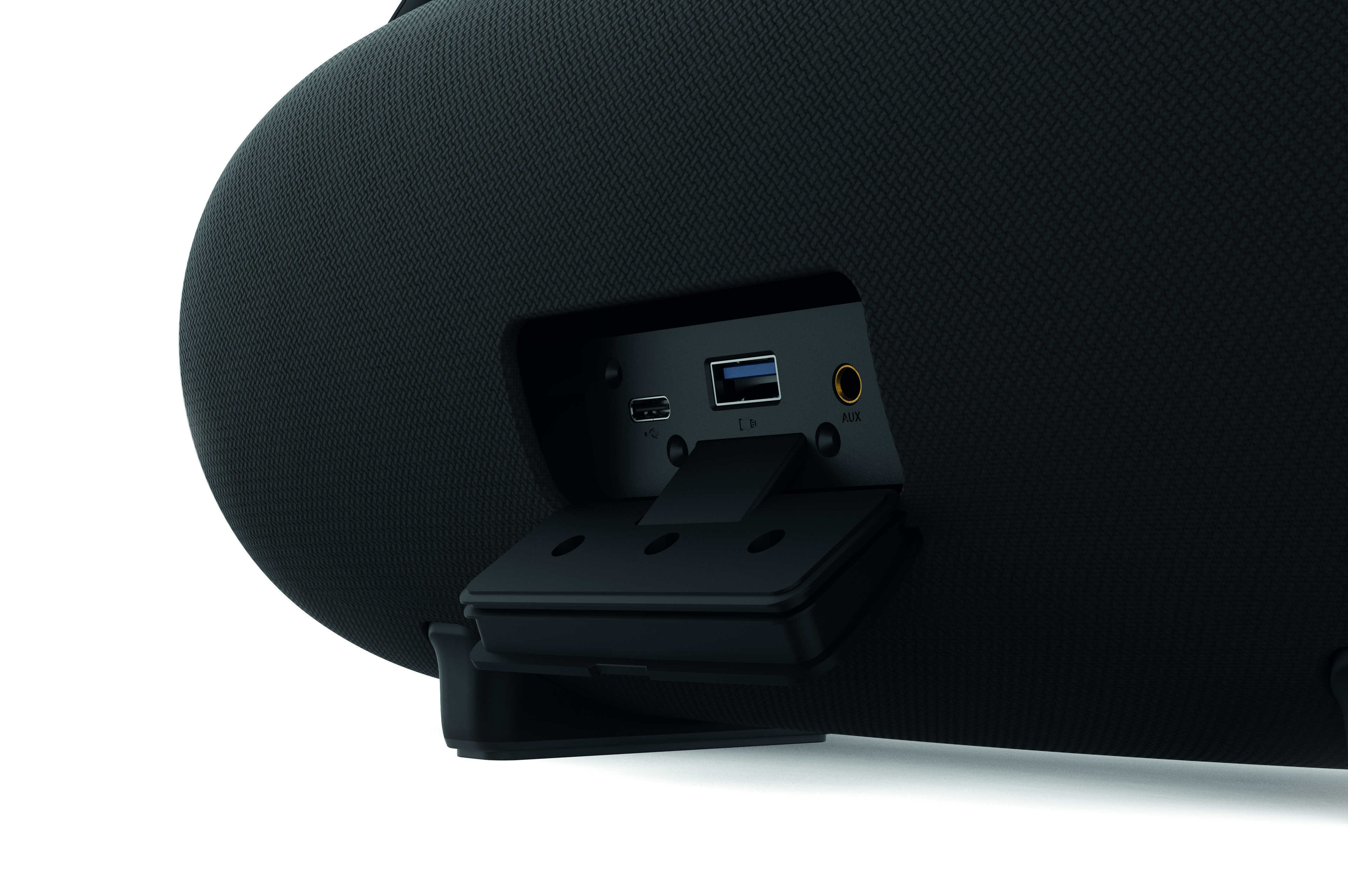 Rückseite eines schwarzen Lautsprechers mit geöffnetem Anschlussfach, das USB-C-, USB- und AUX-Anschlüsse zeigt.