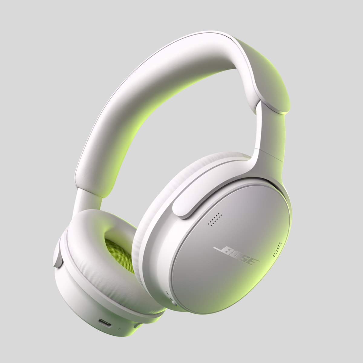 Weiße Bose Over-Ear-Kopfhörer mit grünen Akzenten im Innenraum vor grauem Hintergrund.
