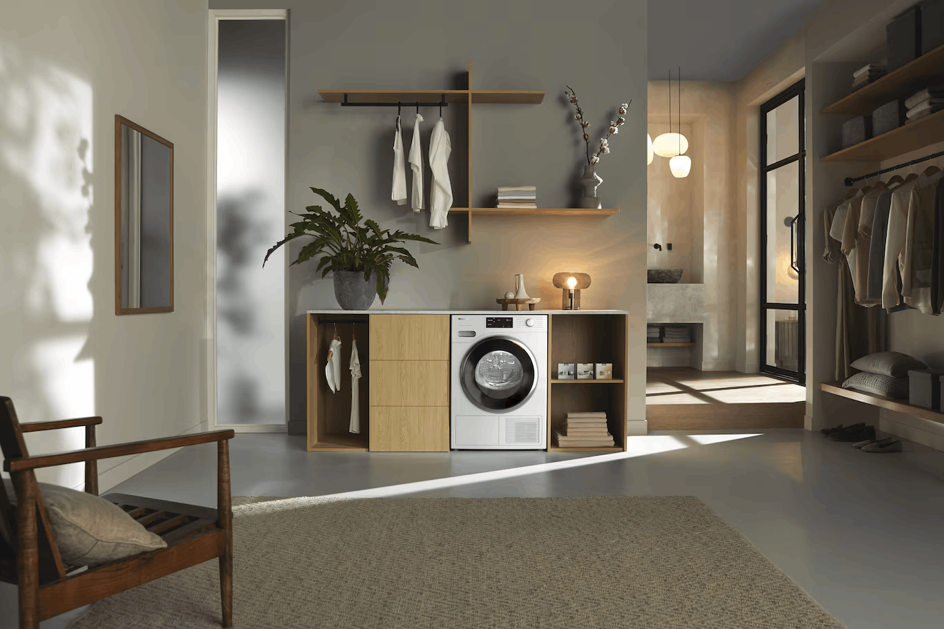Lavadero moderno con muebles de madera, lavadora blanca, plantas y un armario abierto cerca.