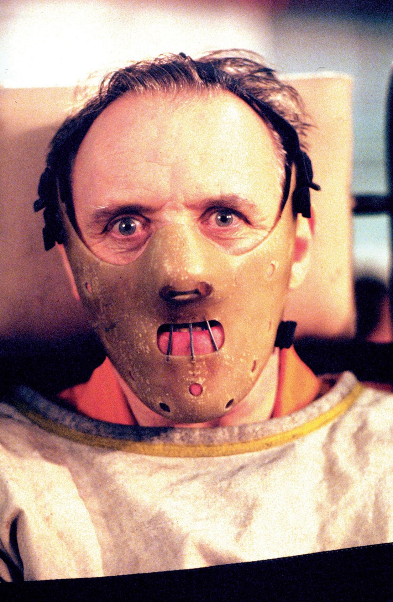 Ein Mann mit kahlem Kopf trägt eine beige Maske mit Metallstäben über dem Mund.