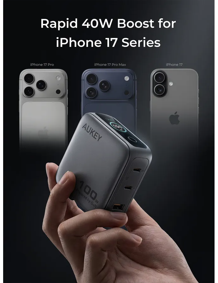 Eine Hand hält ein Aukey 100W GaN-Ladegerät vor dunklem Hintergrund mit drei verschwommenen iPhone 17 Modellen.