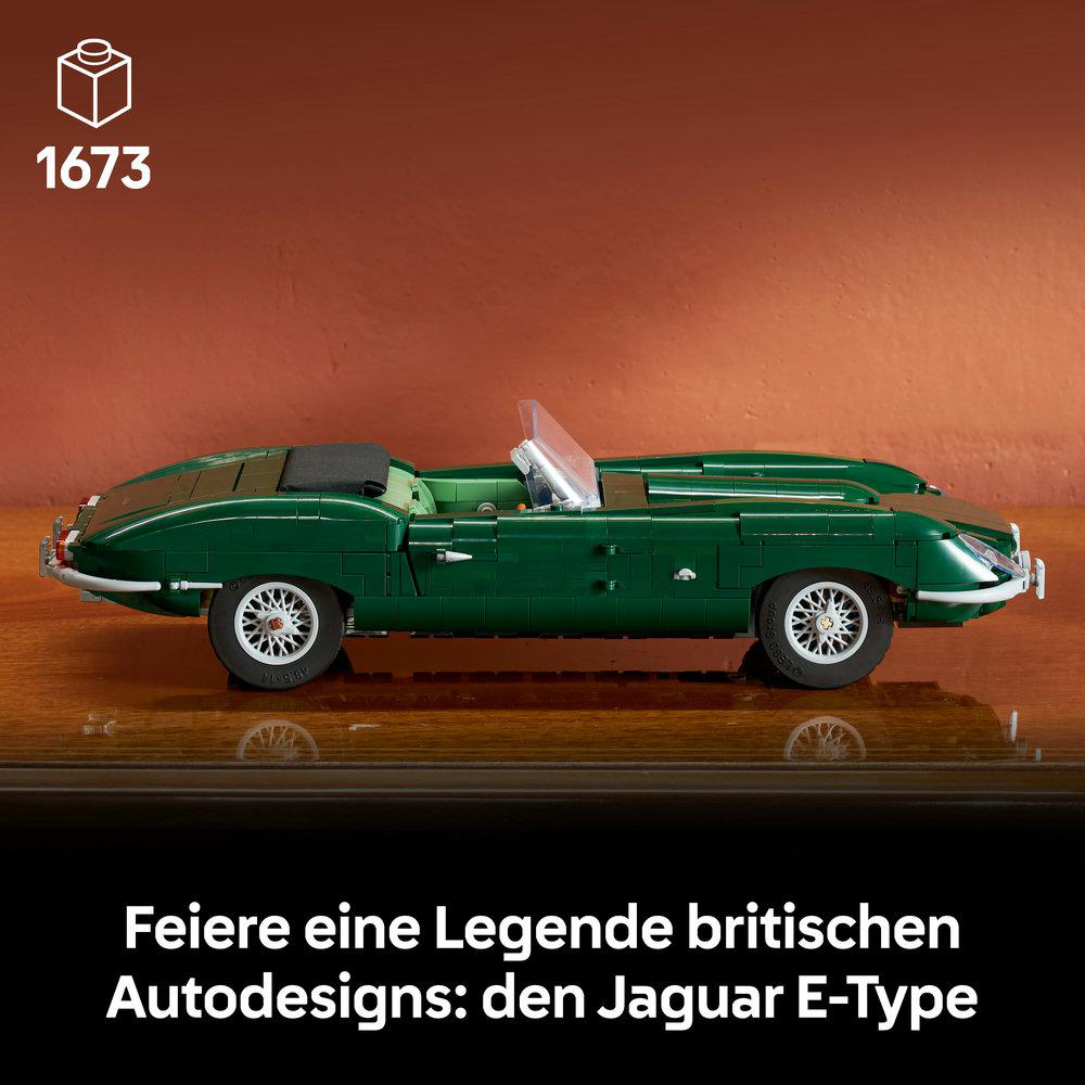 Ein detailliertes LEGO-Modell eines dunkelgrünen Jaguar E-Type Autos auf einer Holzoberfläche vor einer Wand.
