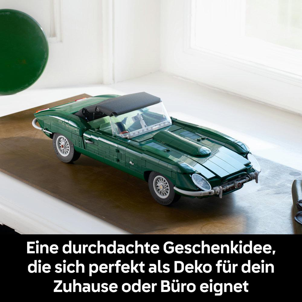 Ein detailliertes grünes Spielzeugauto auf einer Holzoberfläche in einem Zimmer.