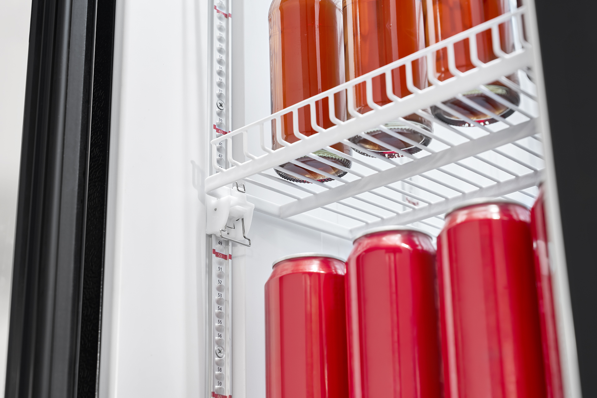 Im weißen Kühlschrank stehen O-Saft-Flaschen oben und rote Getränkedosen unten.