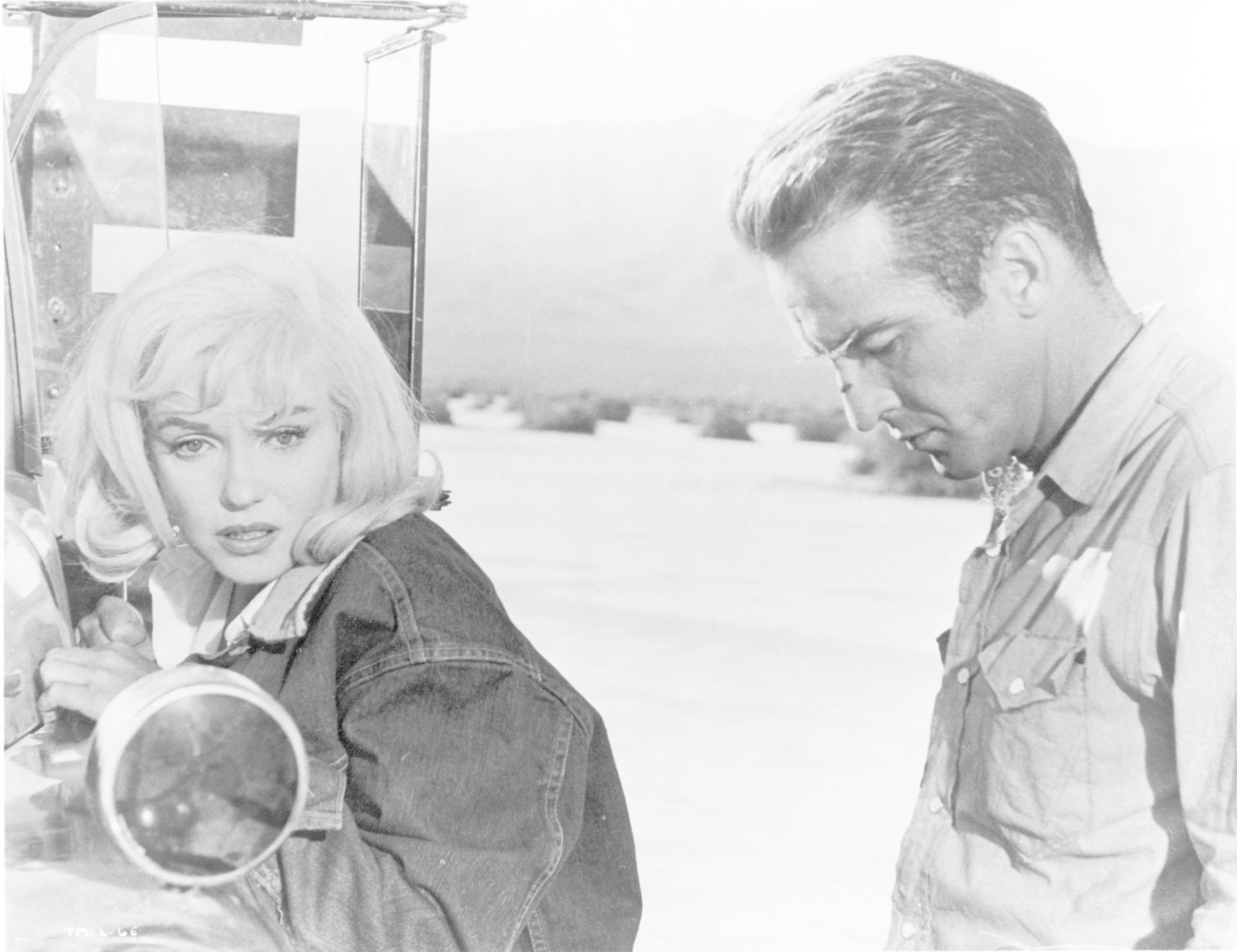 Marilyn Monroe und Montgomery Clift stehen im Freien vor einer hellen, verschwommenen Landschaft.