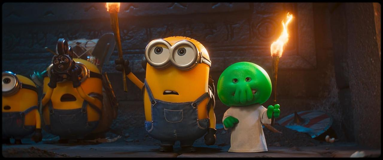 Minions und eine grüne Kreatur halten Fackeln in einer Höhle.