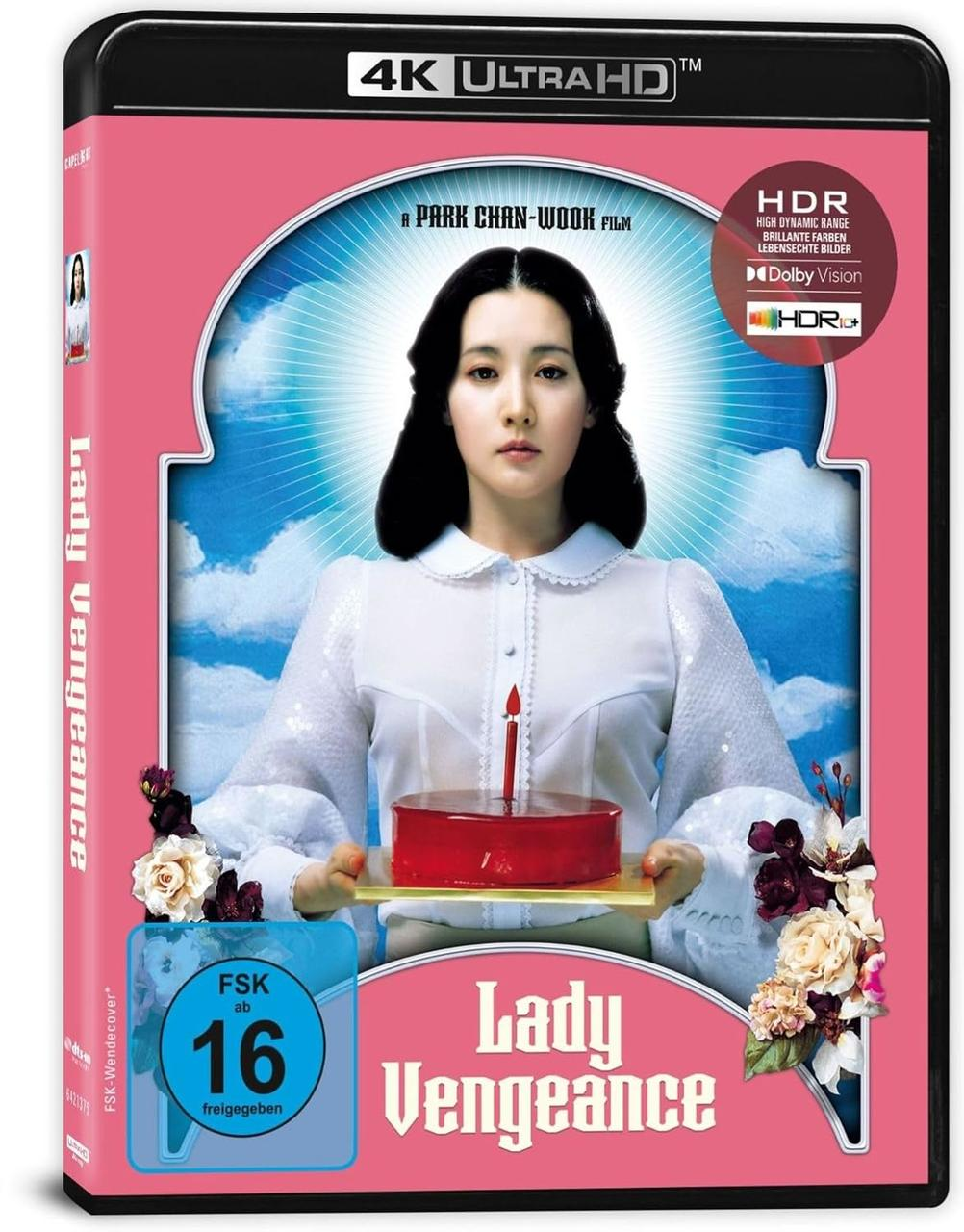 Eine Frau in weißer Kleidung hält einen roten Kuchen mit einer Kerze, umgeben von floralen Elementen und blauem Himmel.