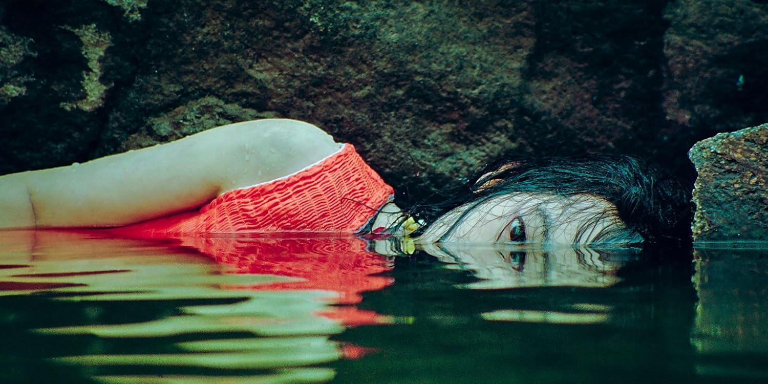 Frau mit rotem Top im Wasser, Gesicht teilweise untergetaucht.