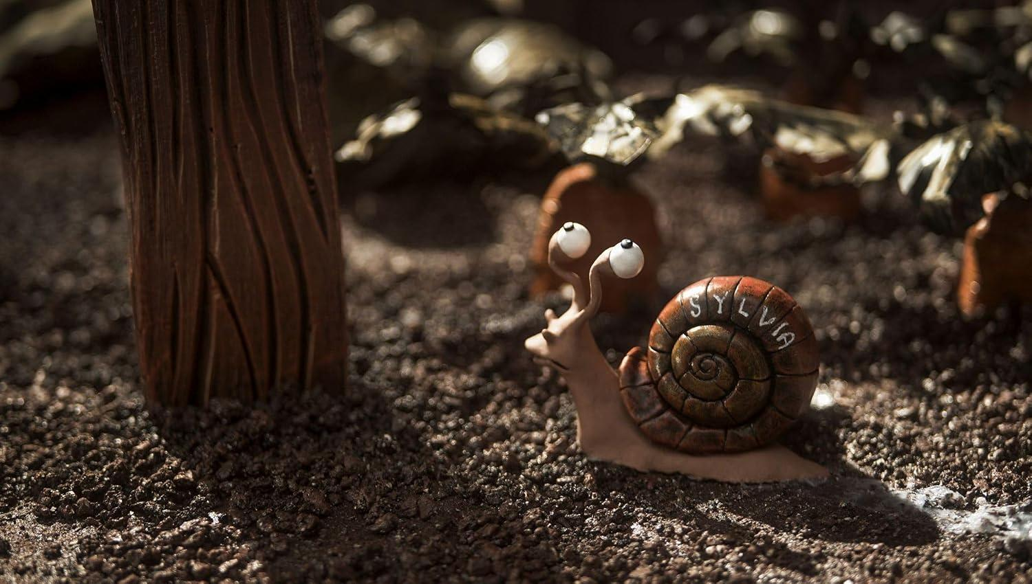 Eine kleine braune Tonschnecke mit dem Namen Sylvia auf dem Haus kriecht auf dunkler Erde.