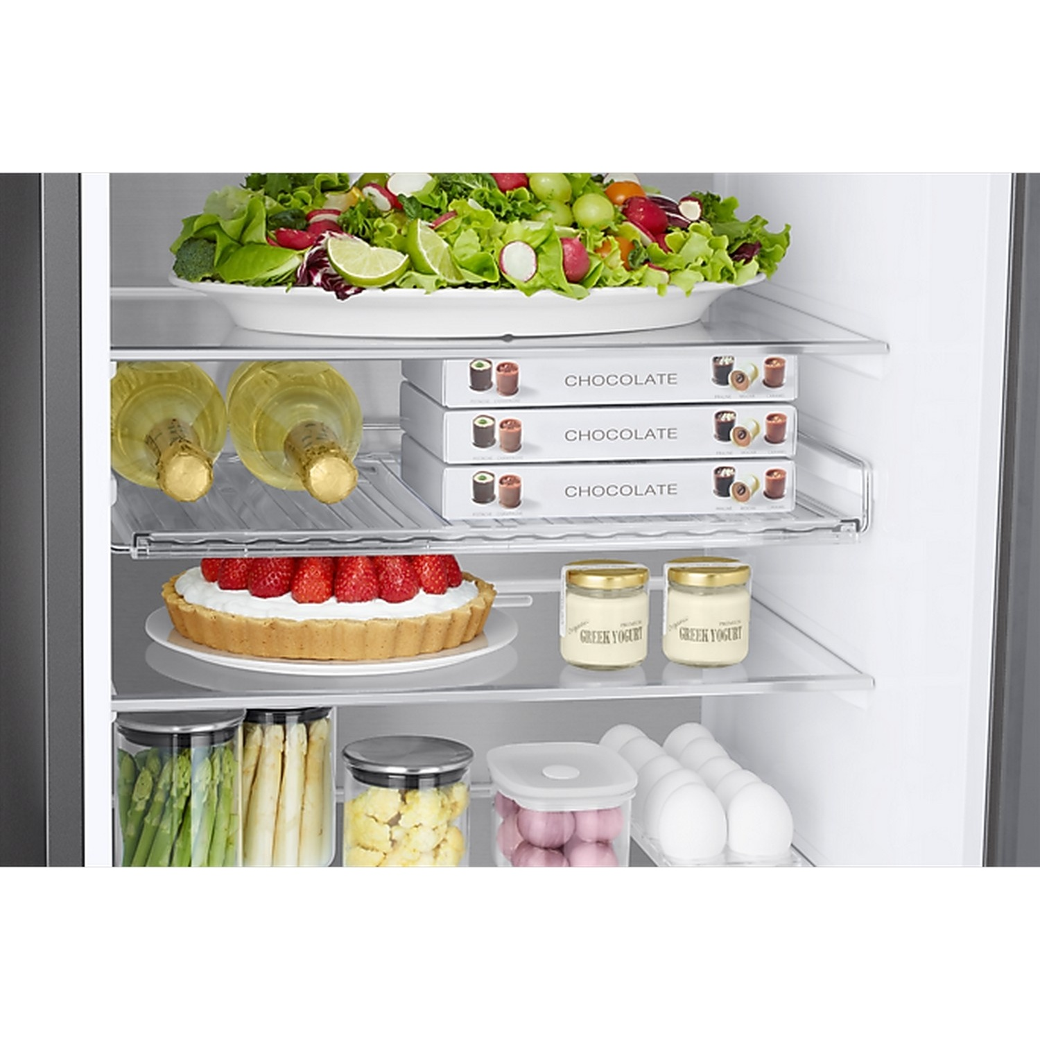 Un réfrigérateur bien approvisionné avec salade, chocolat, vin, gâteau, yaourt, légumes et œufs sur plusieurs étagères.