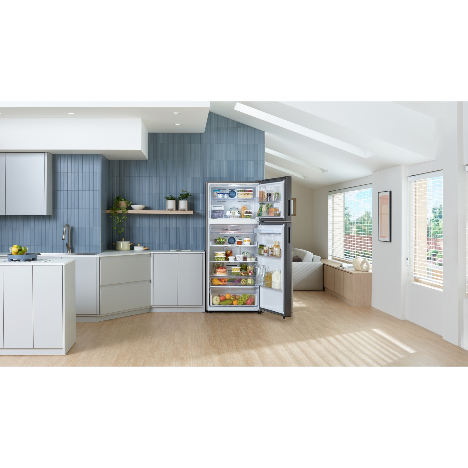 Een moderne open keuken met een open koelkast, licht houten vloeren en blauwe tegelmuren.