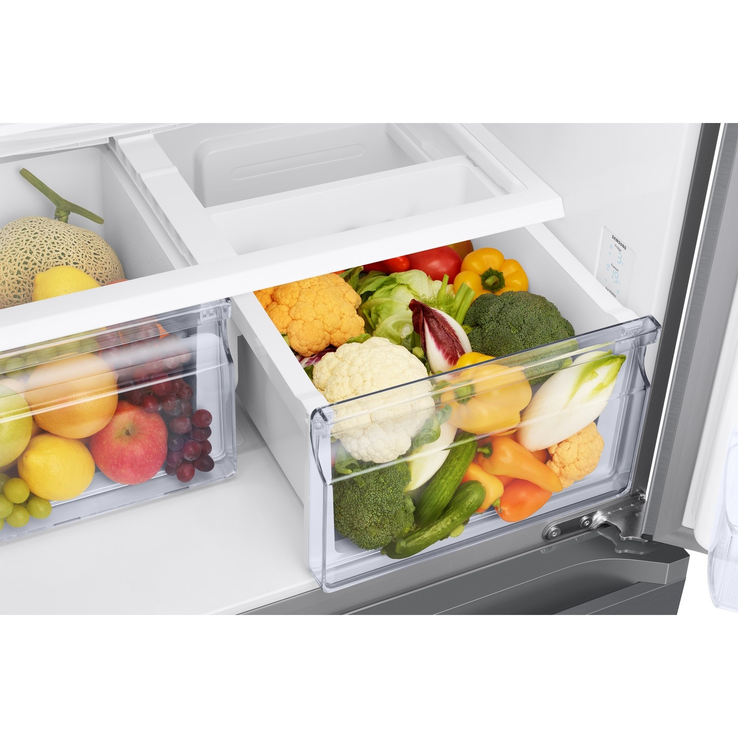 Un réfrigérateur ouvert rempli de légumes et de fruits frais dans des tiroirs transparents.