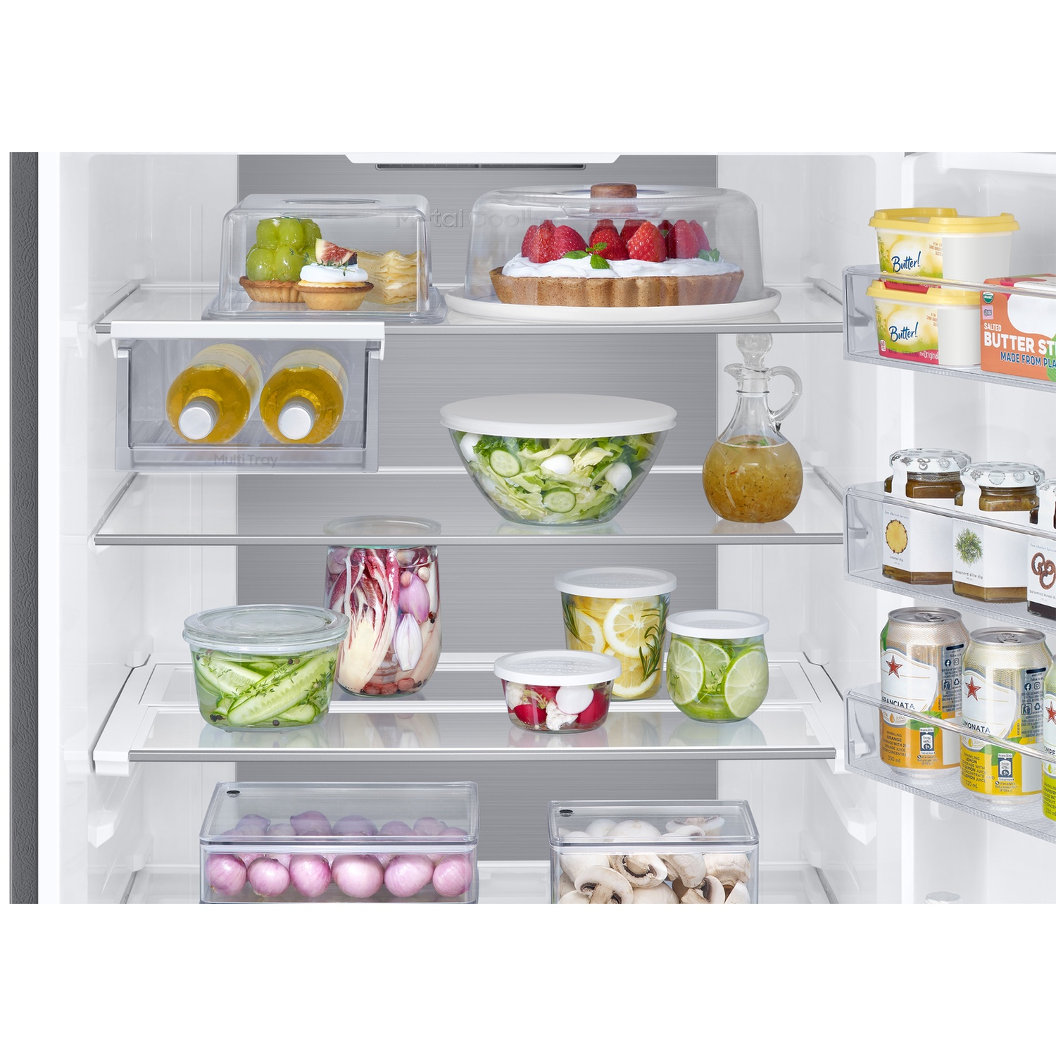 A well-organized white refrigerator filled with fresh fruits, vegetables, salads, beverages, and dairy products.