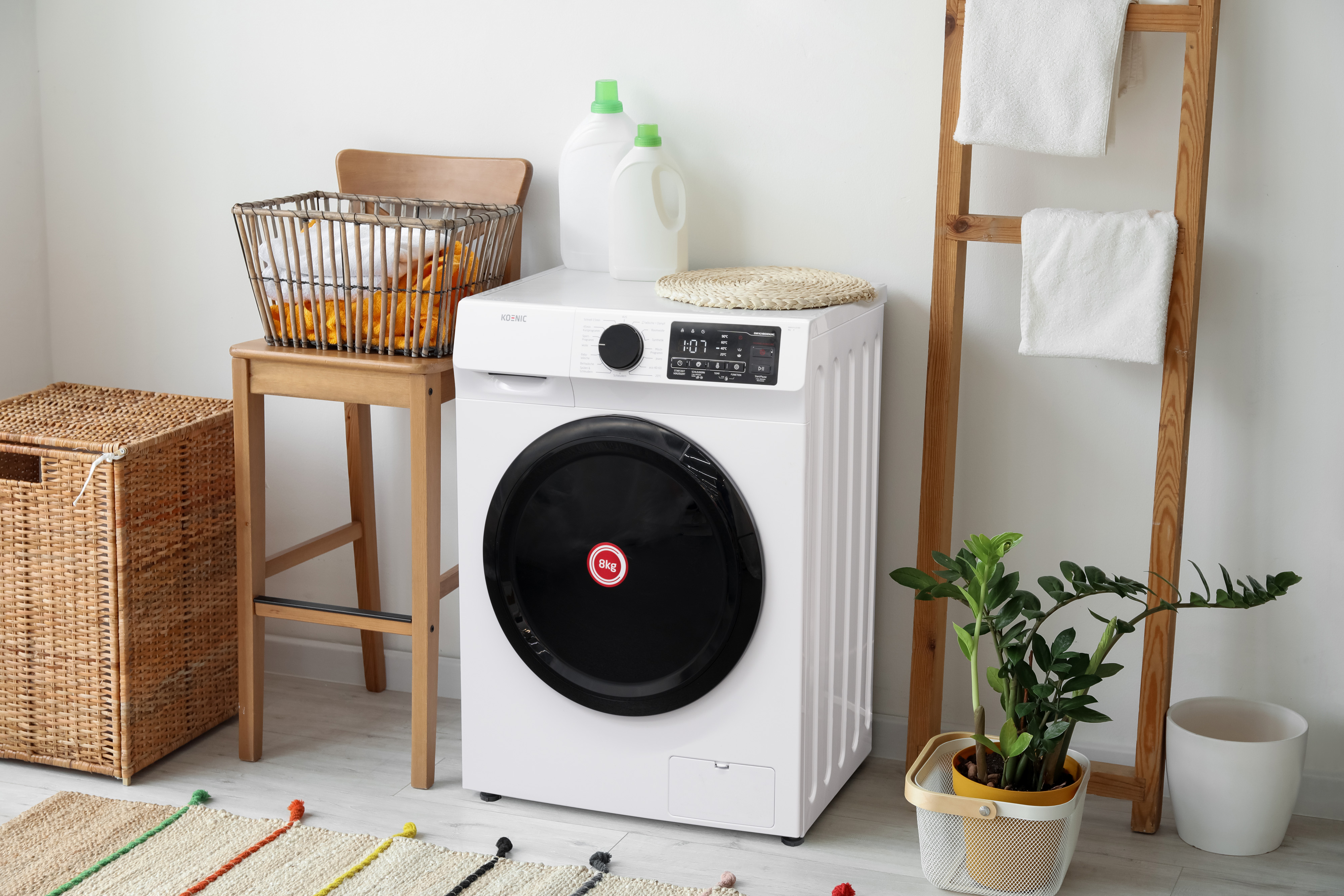 Weiße Waschmaschine in modernem Badezimmer mit Korb, Pflanzen und Handtüchern.