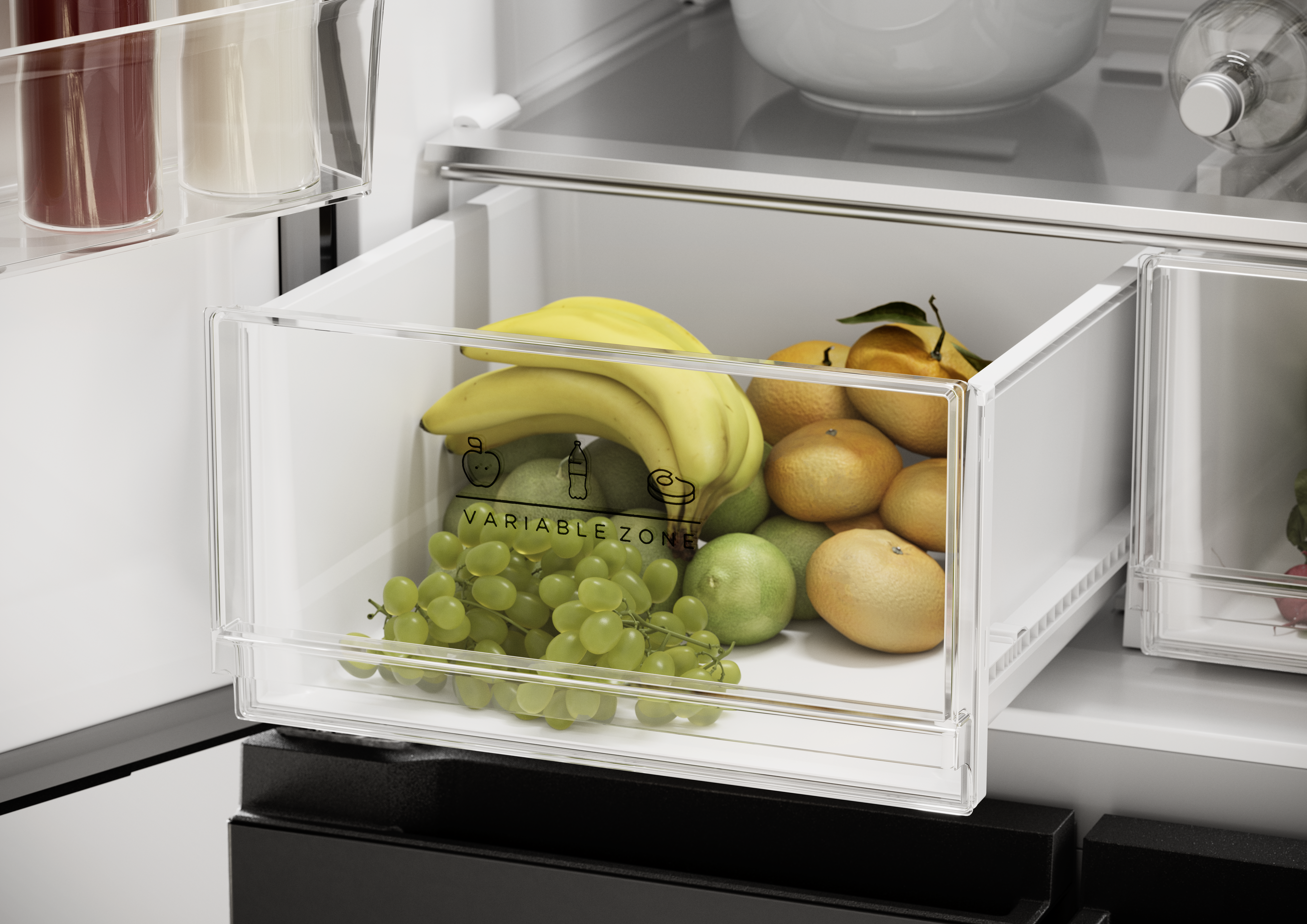 Eine geöffnete Kühlschublade gefüllt mit frischem Obst wie Bananen, Trauben und Orangen.