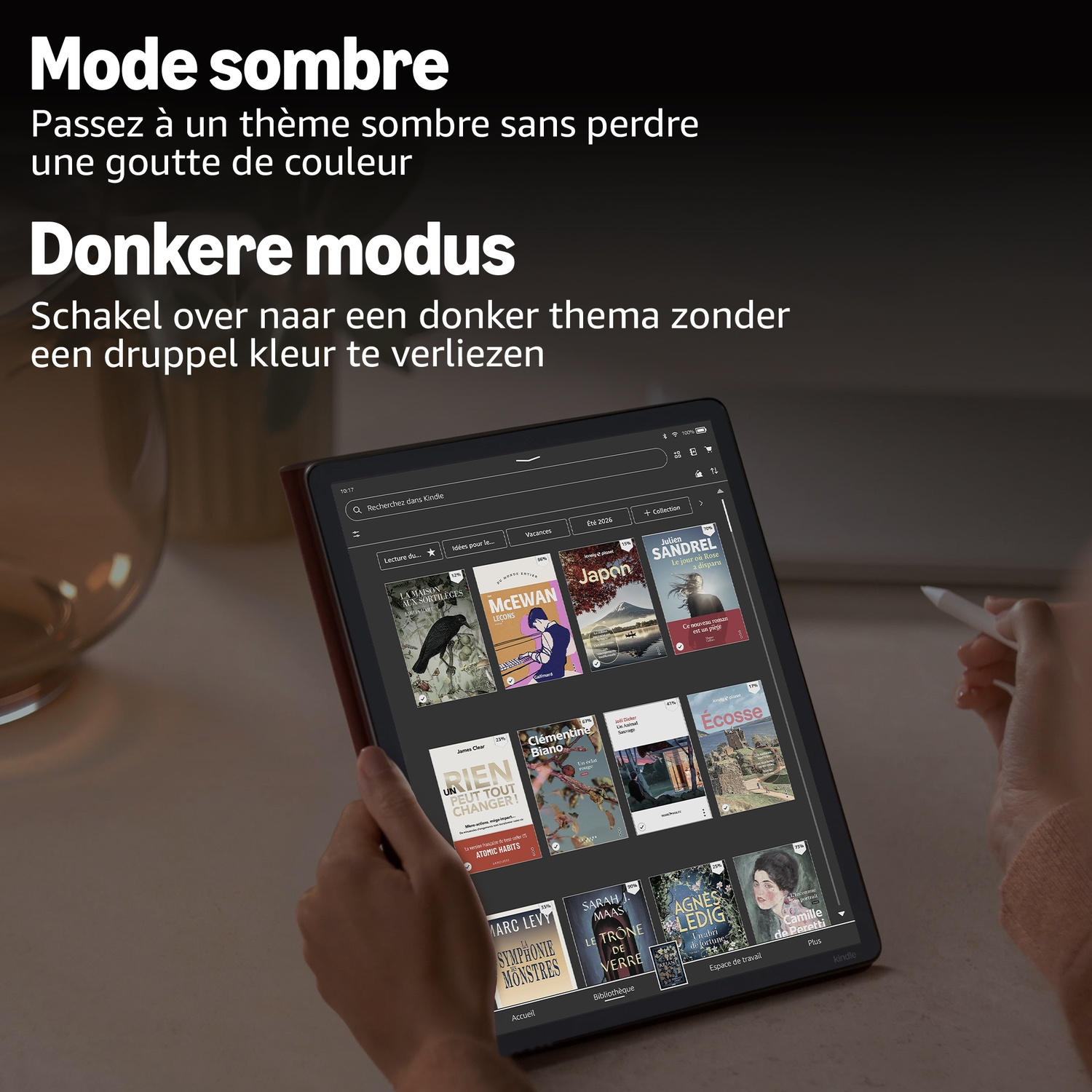 Iemand houdt een Kindle vast met een bibliotheek van kleurrijke boekomslagen.