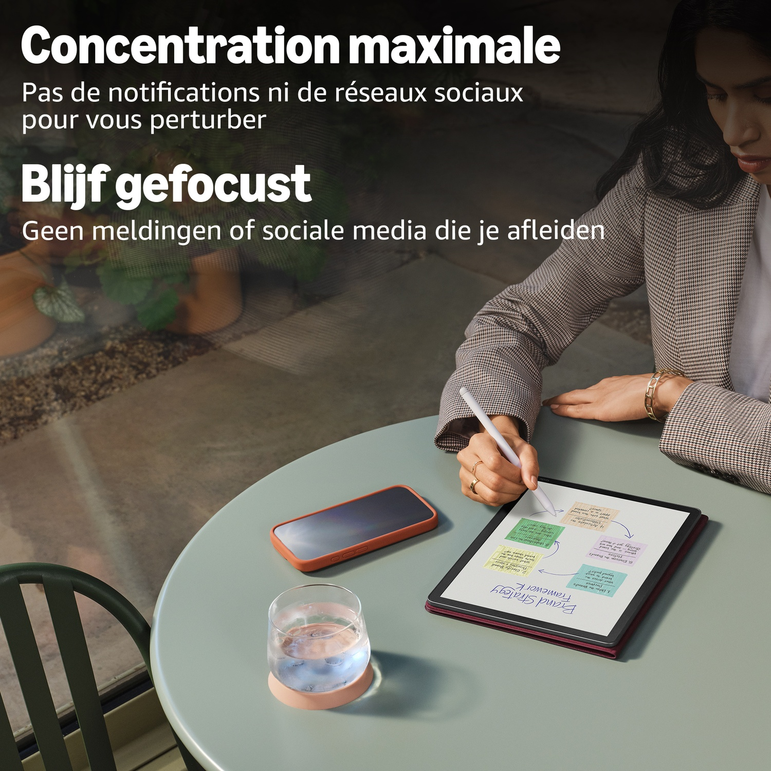 Een vrouw zit aan een tafel te schrijven met een stylus op een tablet.