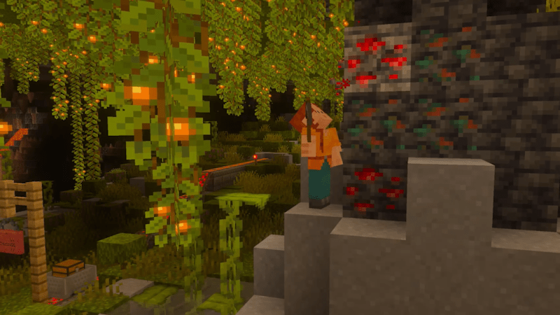 Minecraft-Spieler in einer Höhle mit roten Erzblöcken und hängenden Leuchtbeerenranken.