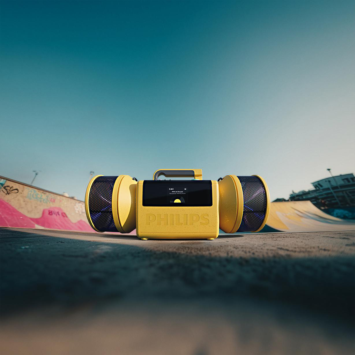Ein gelber Philips Ghettoblaster steht auf Beton in einem Skatepark unter blauem Himmel.
