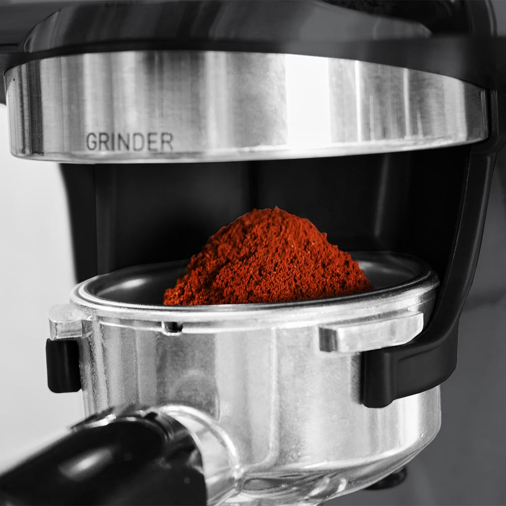 Eine Kaffeemühle füllt einen Siebträger mit gemahlenem Kaffee.