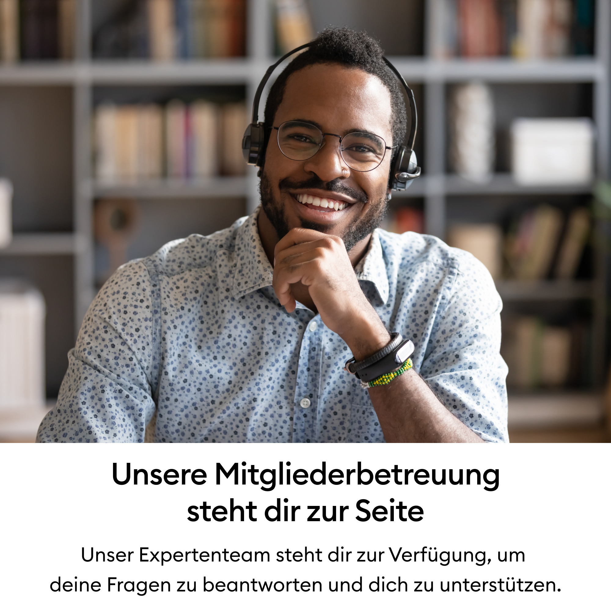 Lächelnter Mann mit Brille und Headset vor einem Bücherregal.