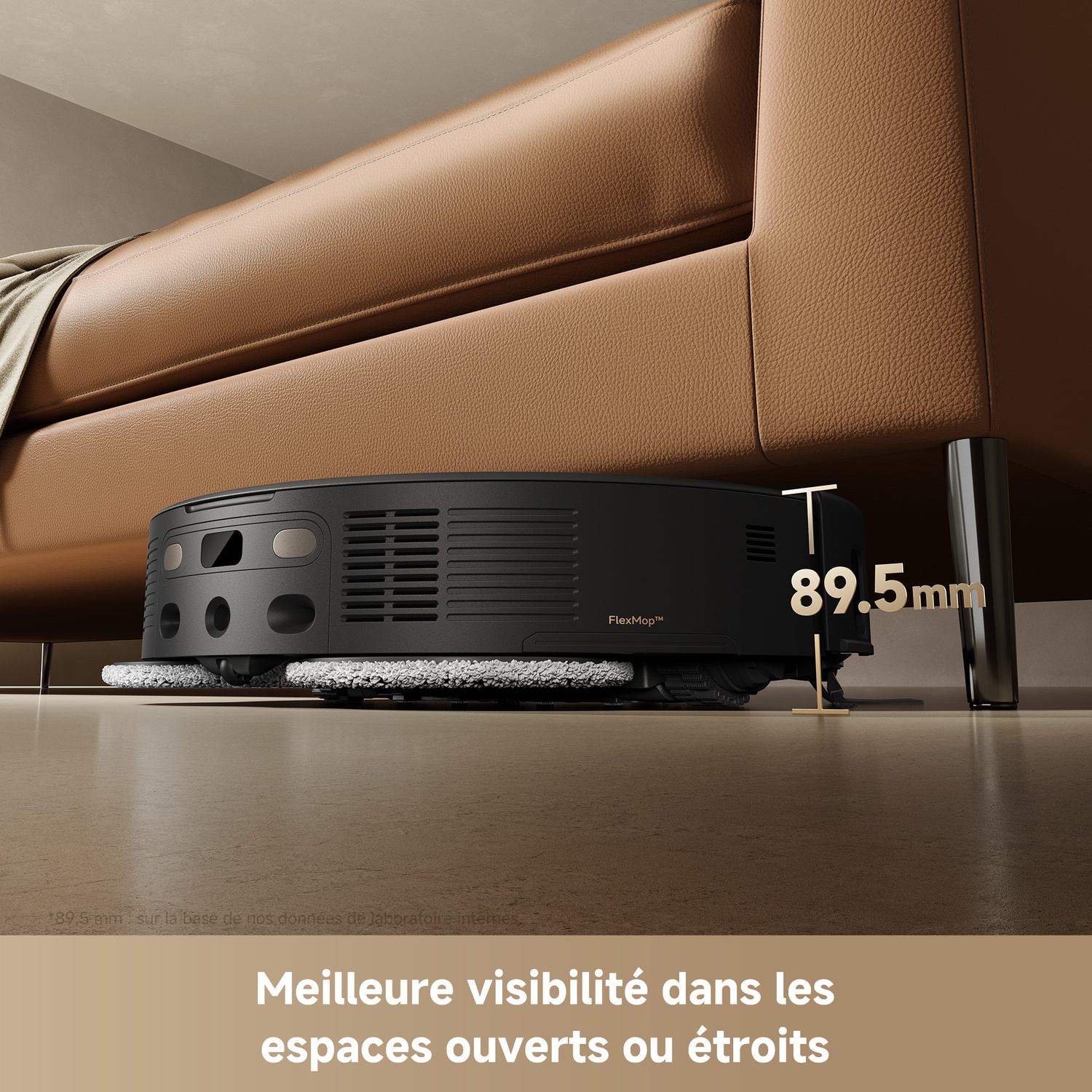 Un robot aspirateur noir nettoie le sol sous un canapé en cuir marron.