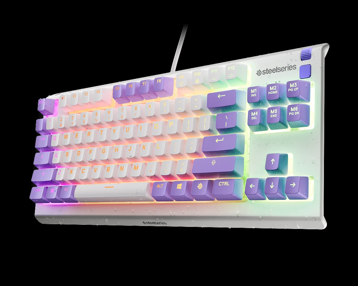 Egy fehér SteelSeries billentyűzet lila és fehér gombokkal, RGB háttérvilágítással, vízcseppekkel borítva.