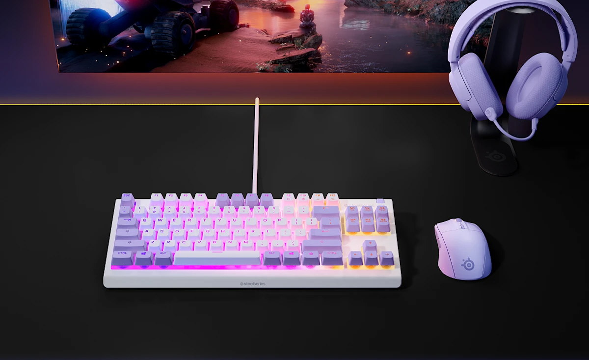 Pasztell lila gamer beállítás megvilágított billentyűzettel, illeszkedő egérrel és fejhallgatóval egy fekete asztalon.