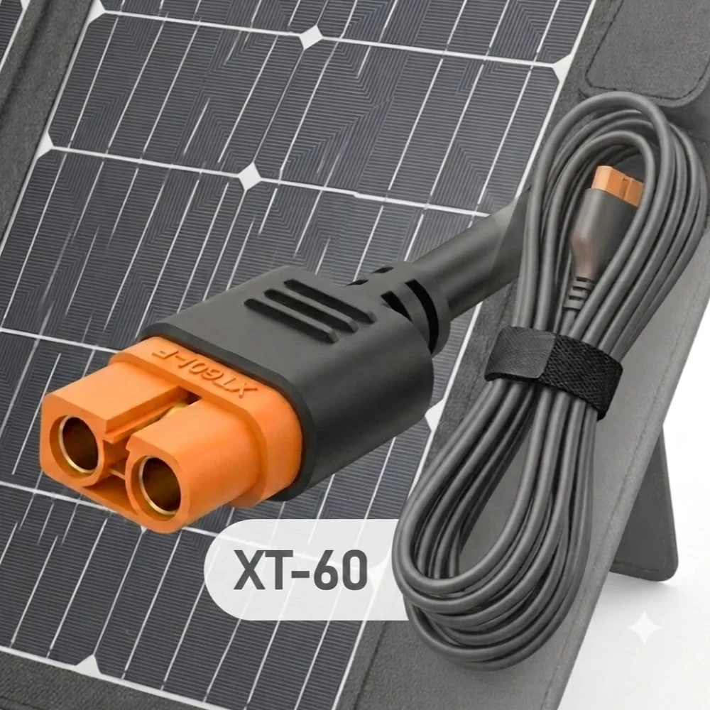 Un cable XT-60 con conectores naranjas y negros se encuentra frente a un pequeño panel solar.