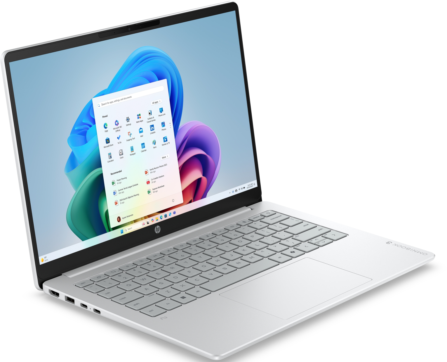 Egy ezüstszínű laptop nyitott képernyőjén a Windows 11 Start menüje és színes grafika látható.