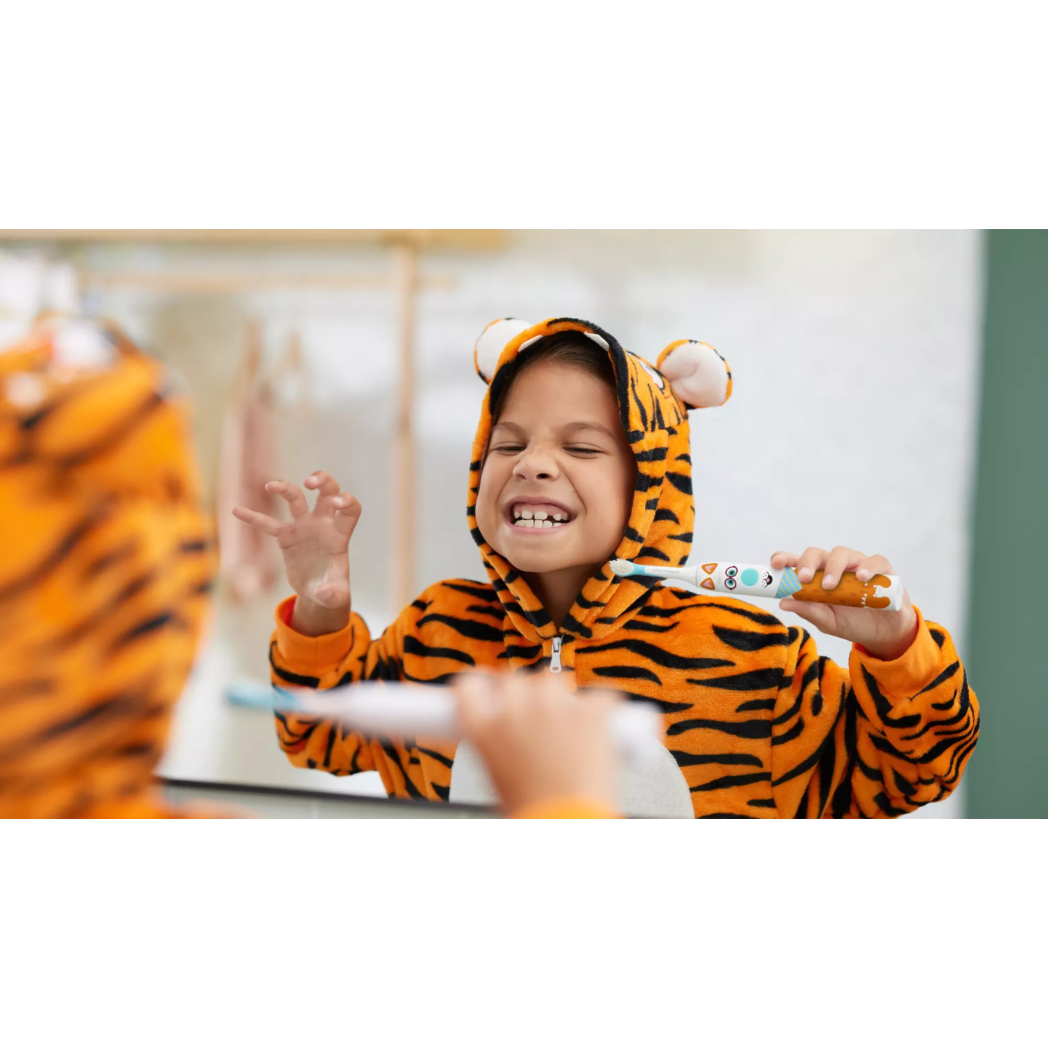 Un bambino in tutina da tigre si lava i denti davanti a uno specchio facendo un gesto giocoso.