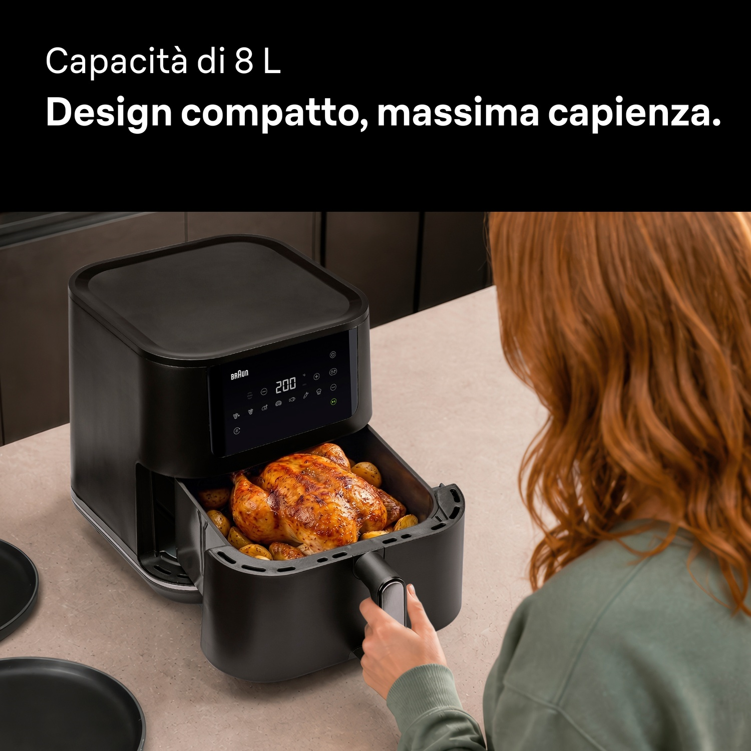 Una donna apre il cassetto di una friggitrice ad aria nera con un pollo intero all'interno.