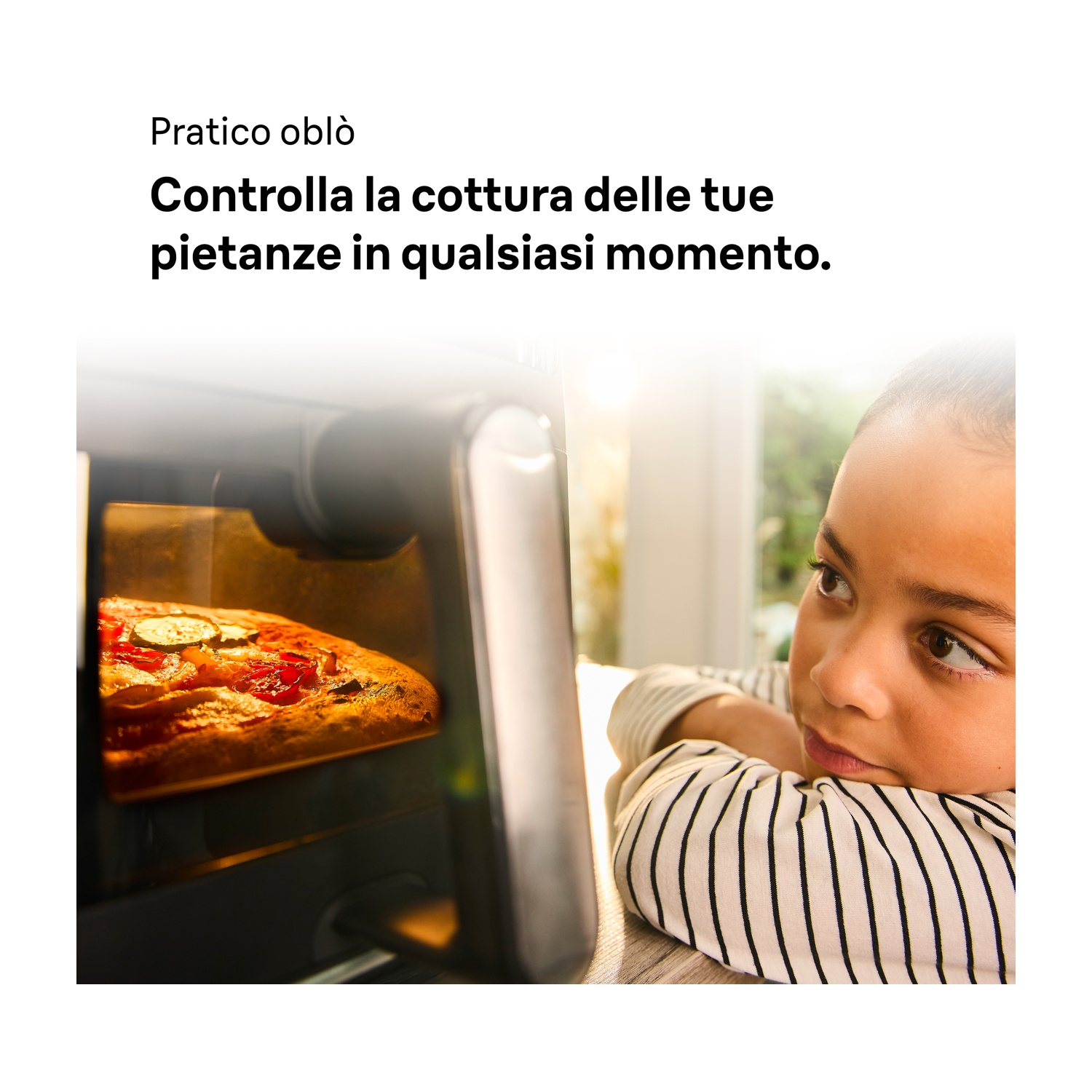 Un bambino guarda curioso attraverso l'oblò una pizza in cottura nel forno. Testo in alto.
