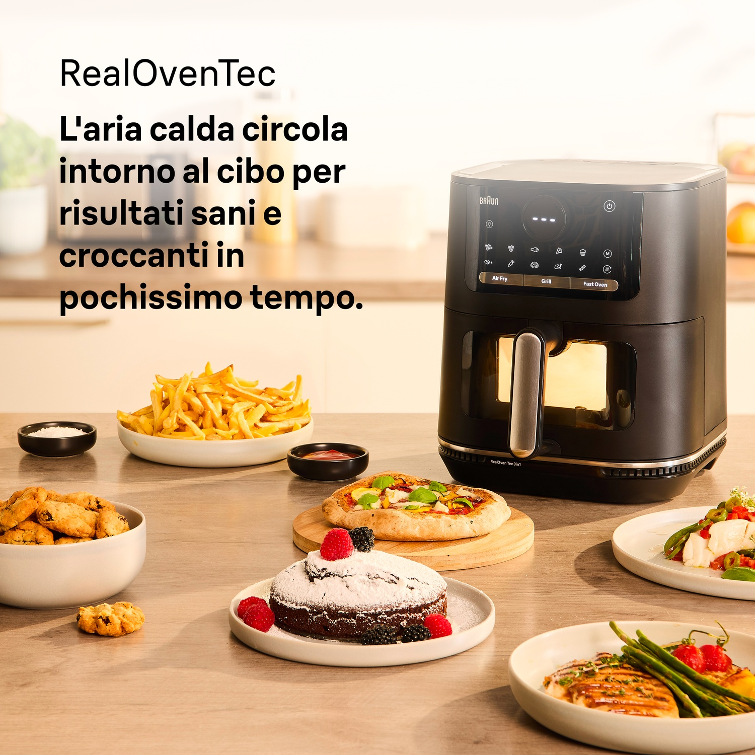 Una friggitrice ad aria nera su un tavolo con piatti come patatine fritte, pizza, una torta e pollo.