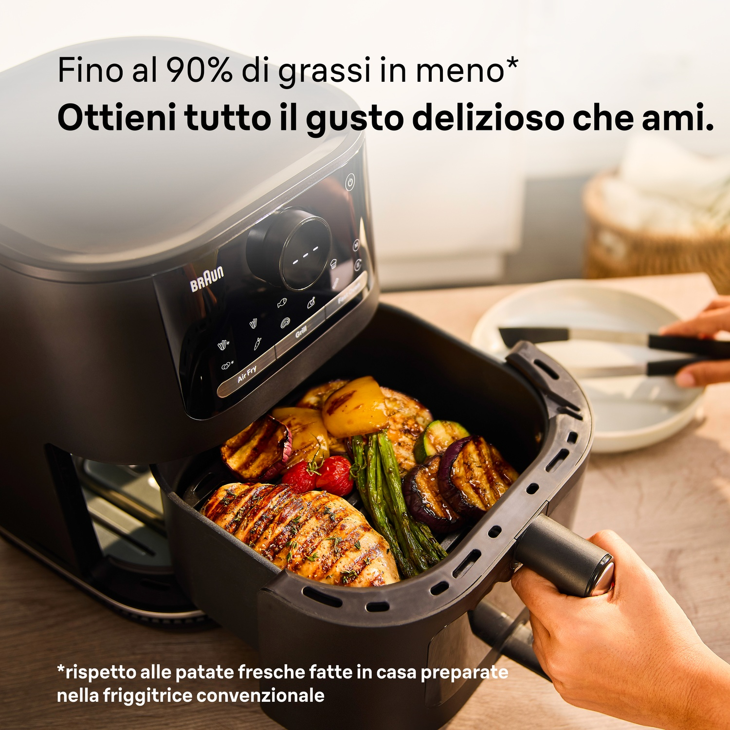 Una friggitrice ad aria nera mostra un cestello pieno di pollo e verdure grigliate.
