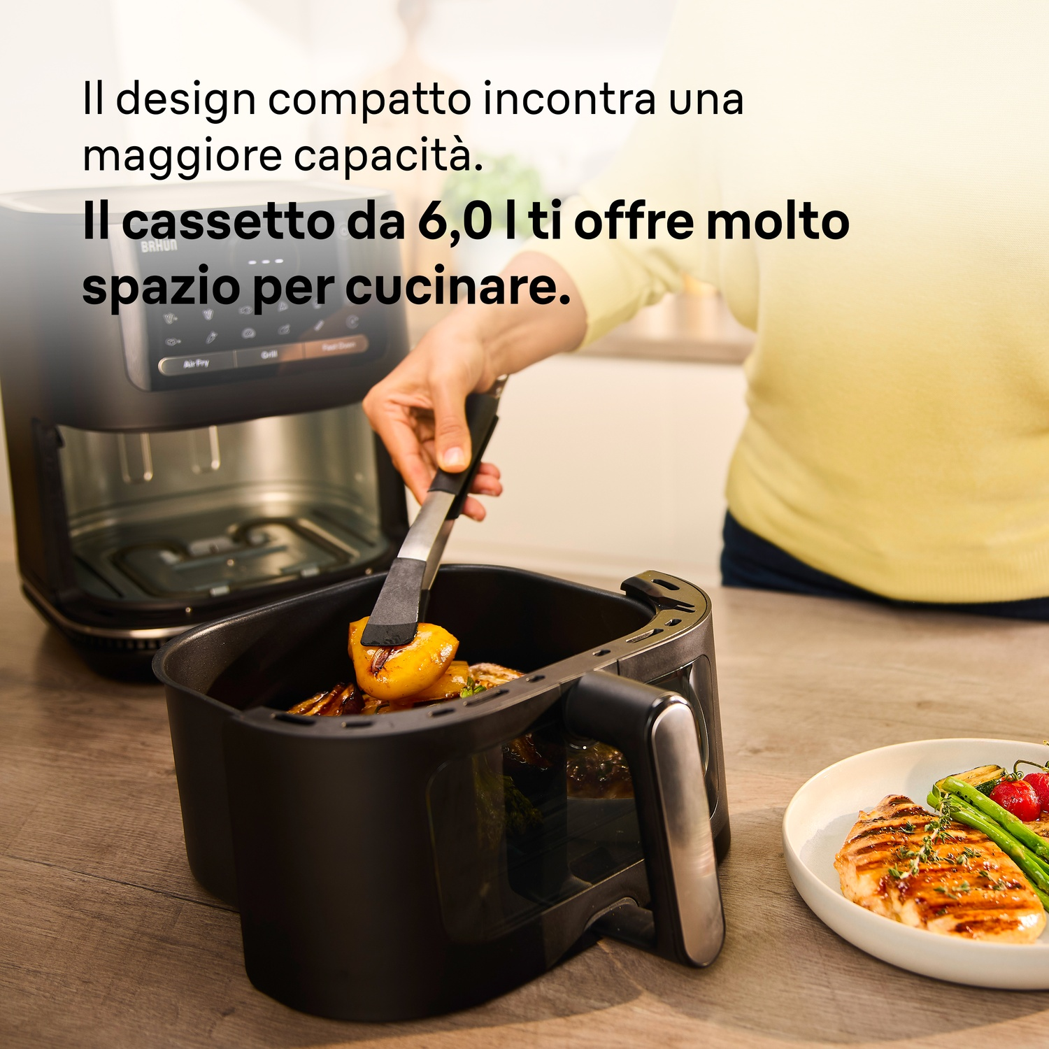 Una persona usa una friggitrice ad aria e rimuove del cibo con le pinze, vicino a un piatto con carne.