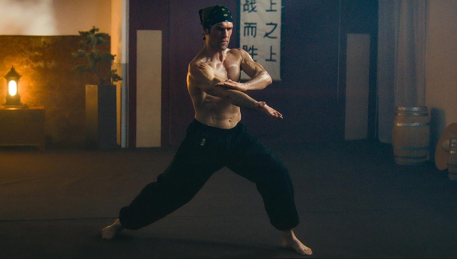 Ein muskulöser Kampfsportler in dunklen Hosen und Bandana übt in einem Dojo eine Kampfkunstform aus.